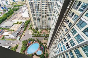 A high-rise building with multiple floors, a swimming pool, and surrounding greenery. - The Landmark Platinum - Vinhomes Central Park (Ho Chi Minh City)