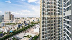 A high-rise building with a grid of windows, surrounded by other buildings and a clear sky. - The Landmark Platinum - Vinhomes Central Park (Ho Chi Minh City)