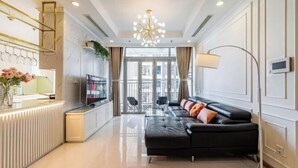 A modern living room with a black leather sofa, a TV, and a glass partition. - The Landmark Platinum - Vinhomes Central Park (Ho Chi Minh City)
