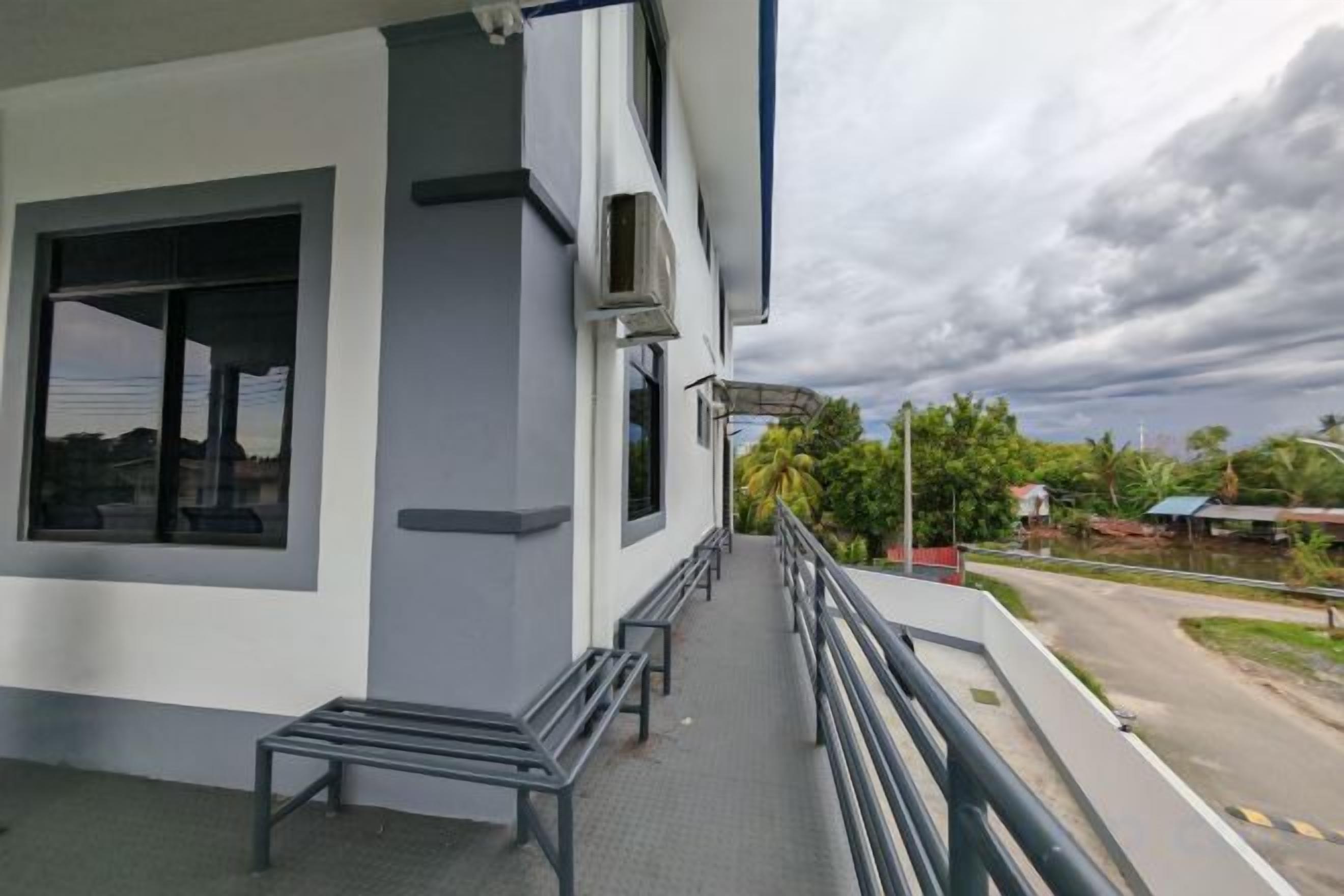 Un edificio con balcón, una banca y vistas a una carretera y follaje.