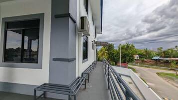 Un edificio con balcón, una banca y vistas a una carretera y follaje.