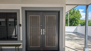 A double door with horizontal slats, a bench, and a red mat with "WELCOME" on it. - Riverside Lot No.1 Homestay at Kota Kinabalu (Putatan)