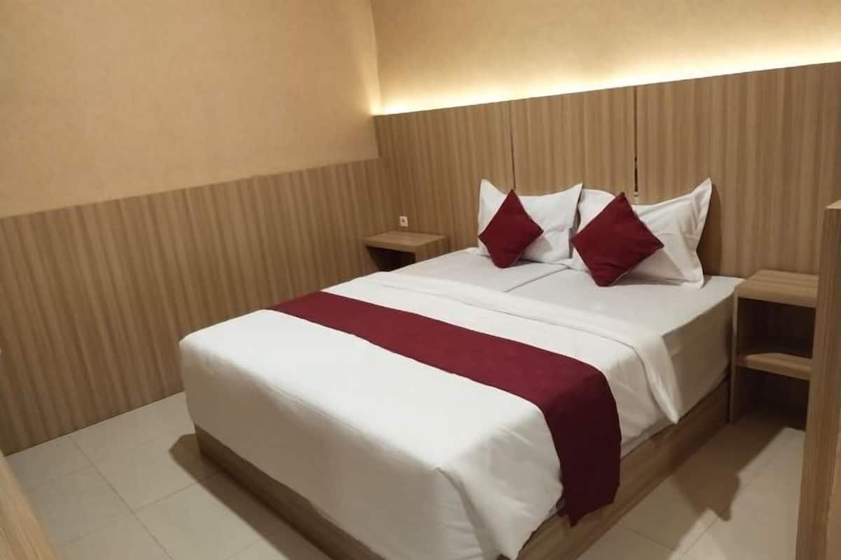 A hotel room with a bed, a nightstand, and a wooden headboard.