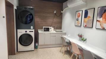 Una cocina compacta con lavadora, microondas y fregadero.