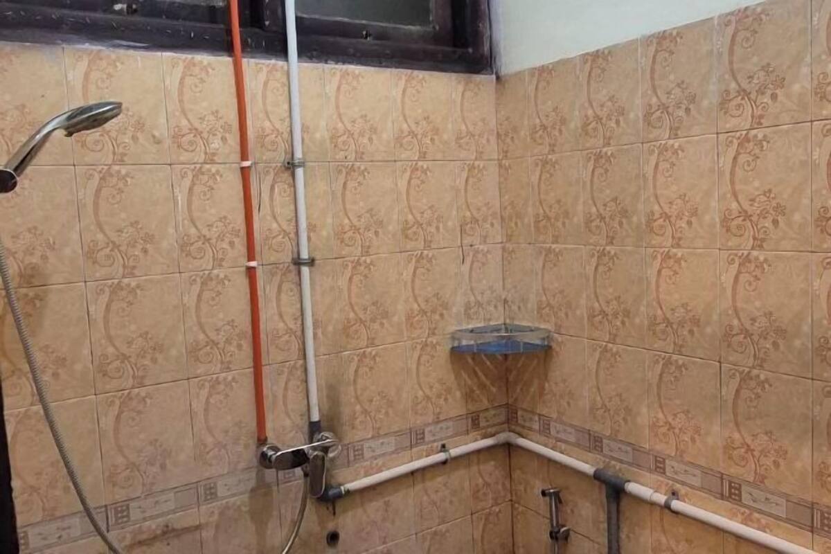 A corner shower area with tiled walls and a corner sink.