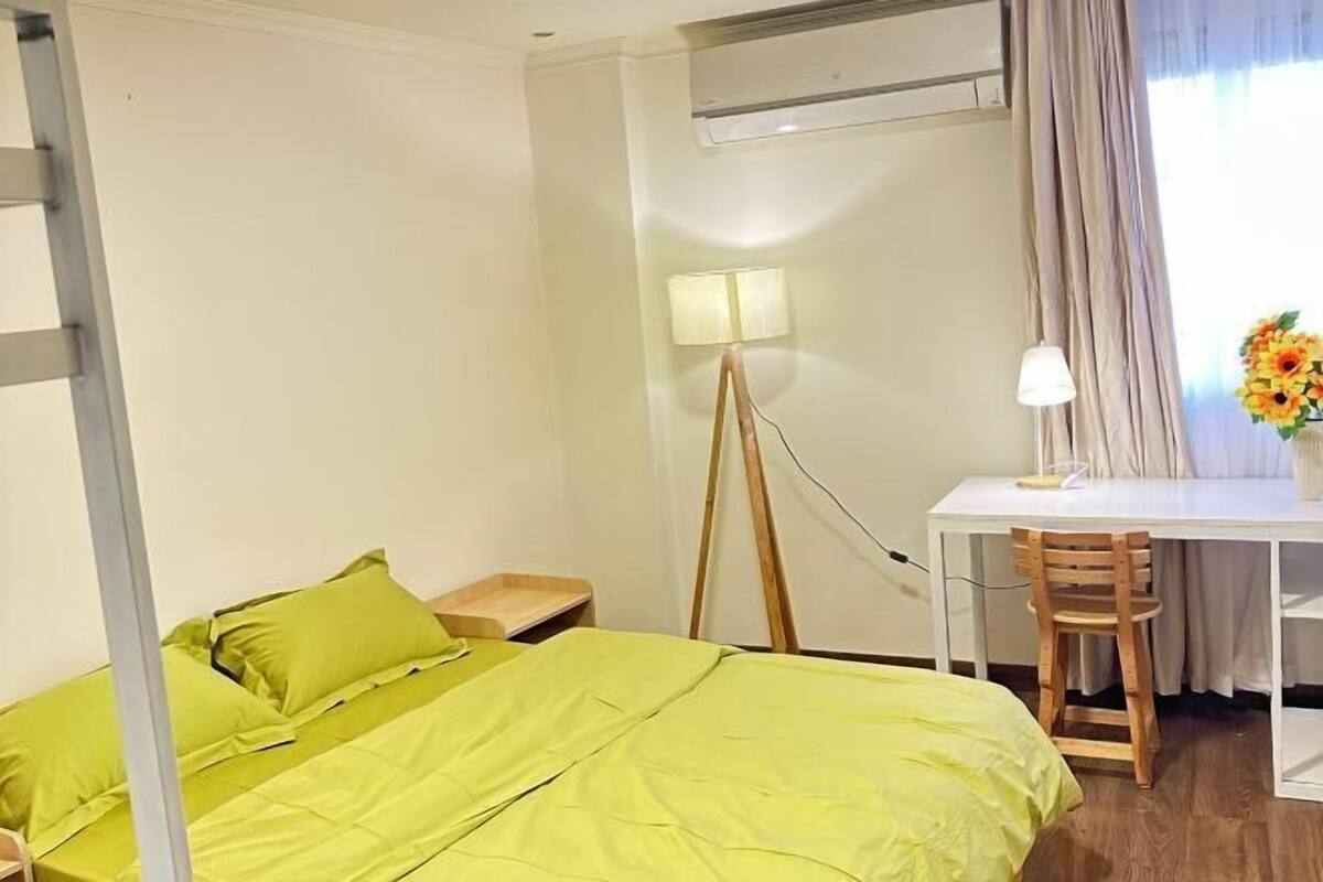 A room with a bed, a desk, a chair, a floor lamp, and a window with curtains.