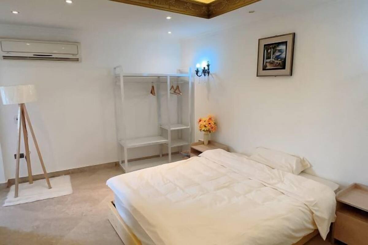 A bedroom with a bed, a wardrobe, a desk, and a lamp.