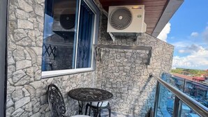 Ein Balkon mit einer Steinmauer, einem kleinen Tisch und einem Stuhl sowie einer Klimaanlage.