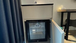 Eine kleine Küche mit integriertem Kühlschrank, einer kleinen Arbeitsfläche und einem Tisch mit Taschentuchbox.