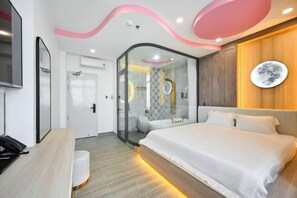 A modern hotel room with a large bed, a desk, a glass-enclosed shower, and a wooden accent wall. - Lotus Airport Hotel Saigon (Ho Chi Minh City)