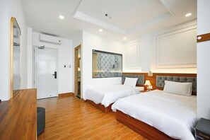 A hotel room with two beds, wooden flooring, a mirror, a door, and a wall-mounted artwork. - Lotus Airport Hotel Saigon (Ho Chi Minh City)
