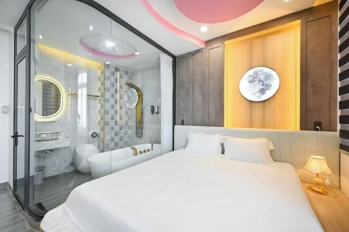 A modern bedroom with a large bed, a glass-enclosed shower, and a wooden accent wall.
