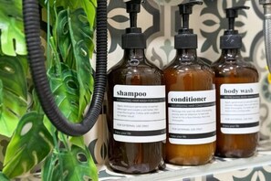 Three bottles of shampoo, conditioner, and body wash on a shelf. - 3 Bedroom NORDIC HOME Full Kitchen 8 MINS to MRT & JODD Fair (Bangkok)