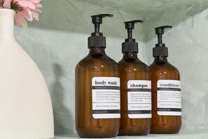 Three brown bottles with black pumps labeled body wash, shampoo, and conditioner on a shelf. - 3 Bedroom NORDIC HOME Full Kitchen 8 MINS to MRT & JODD Fair (Bangkok)