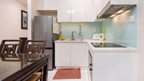 Una cocina compacta con gabinetes blancos, estufa integrada y un lavamanos pequeño.
