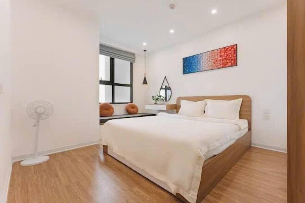 Un dormitorio moderno con una cama de madera, una mesita de noche, una lámpara de pie y una ventana con persianas.