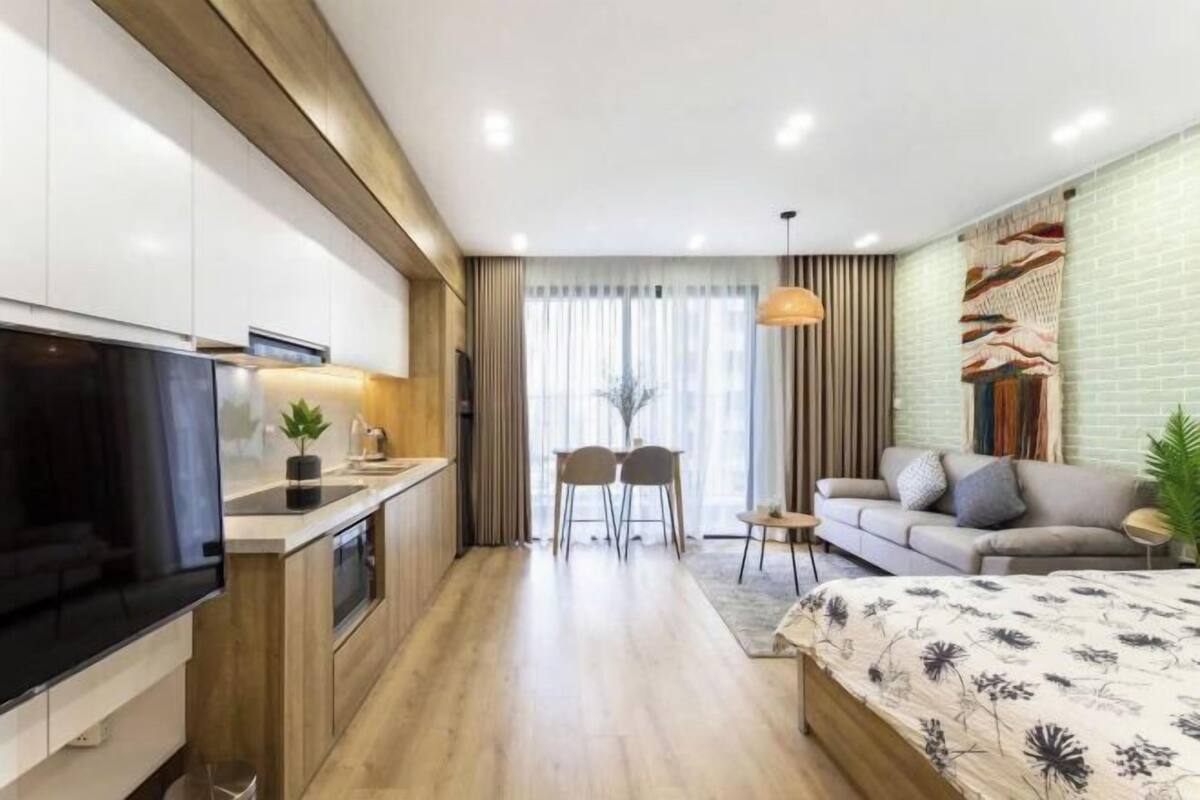 Una habitación de hotel moderna con área de cocina, una mesa de comedor con sillas, un sofá y una cama grande.