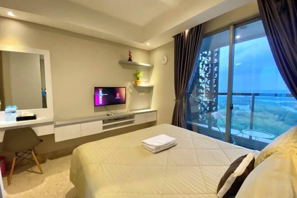 Une chambre d’hôtel équipée d’un lit, d’une télévision, d’un bureau et d’une grande fenêtre donnant sur un beau paysage.
