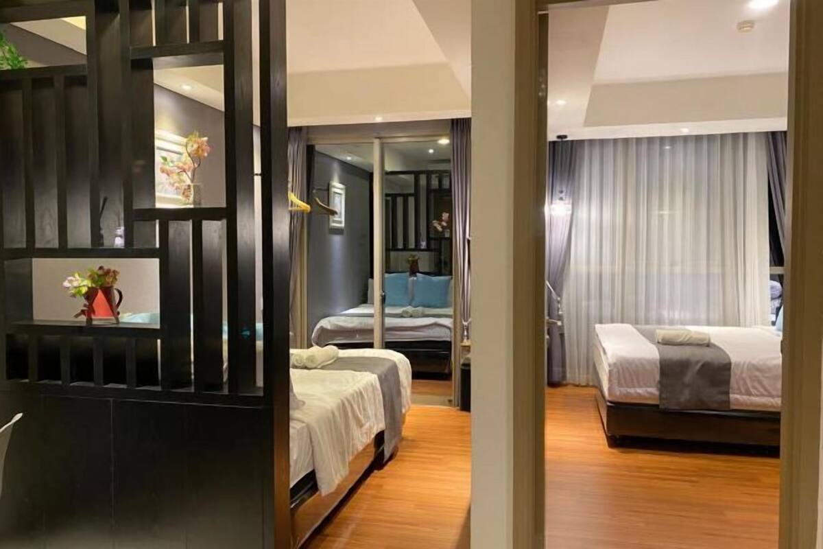 Une chambre d’hôtel avec un plancher en bois, deux lits, un bureau et une vue sur l’extérieur, visible à travers une porte vitrée.