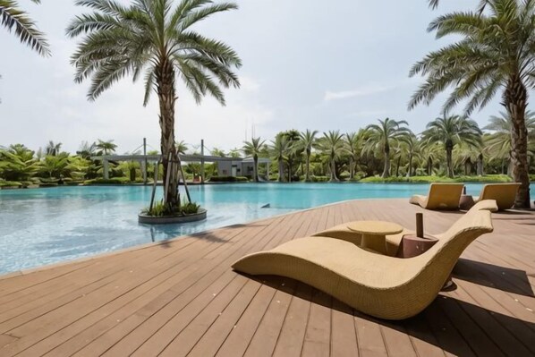 A wooden deck with lounge chairs and a pool.