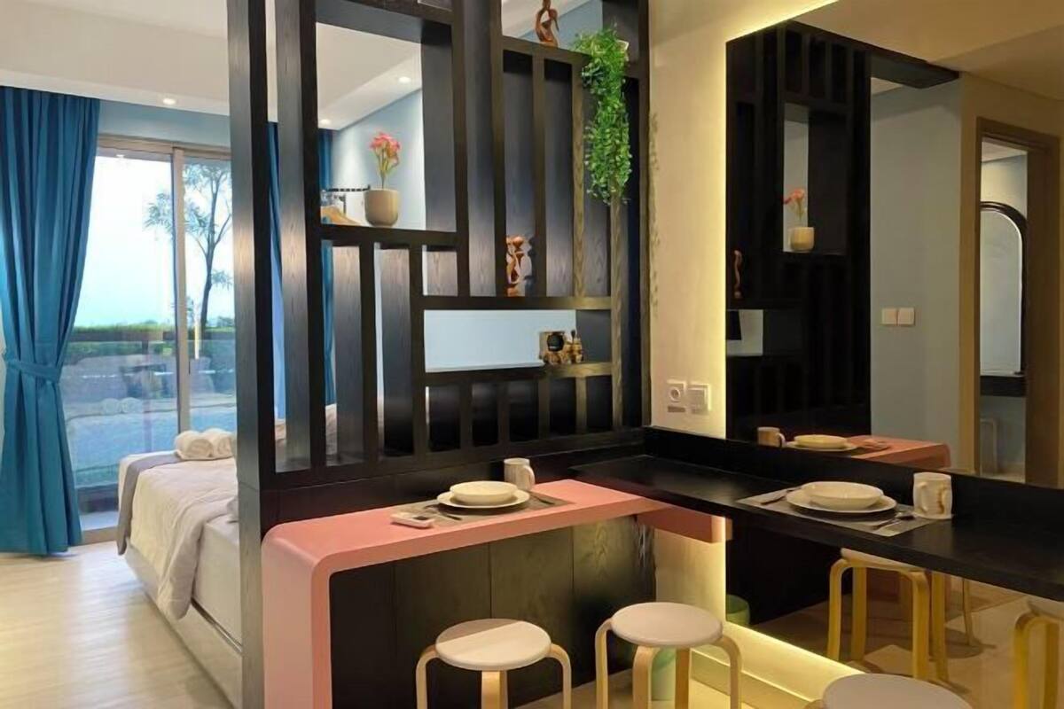 Une chambre d’hôtel moderne dotée d’une kitchenette, d’un lit avec vue et d’un coin repas avec des tabourets.