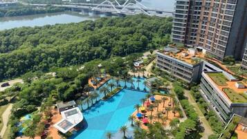 A high-rise building with a rooftop pool and a view of a bridge over a river.