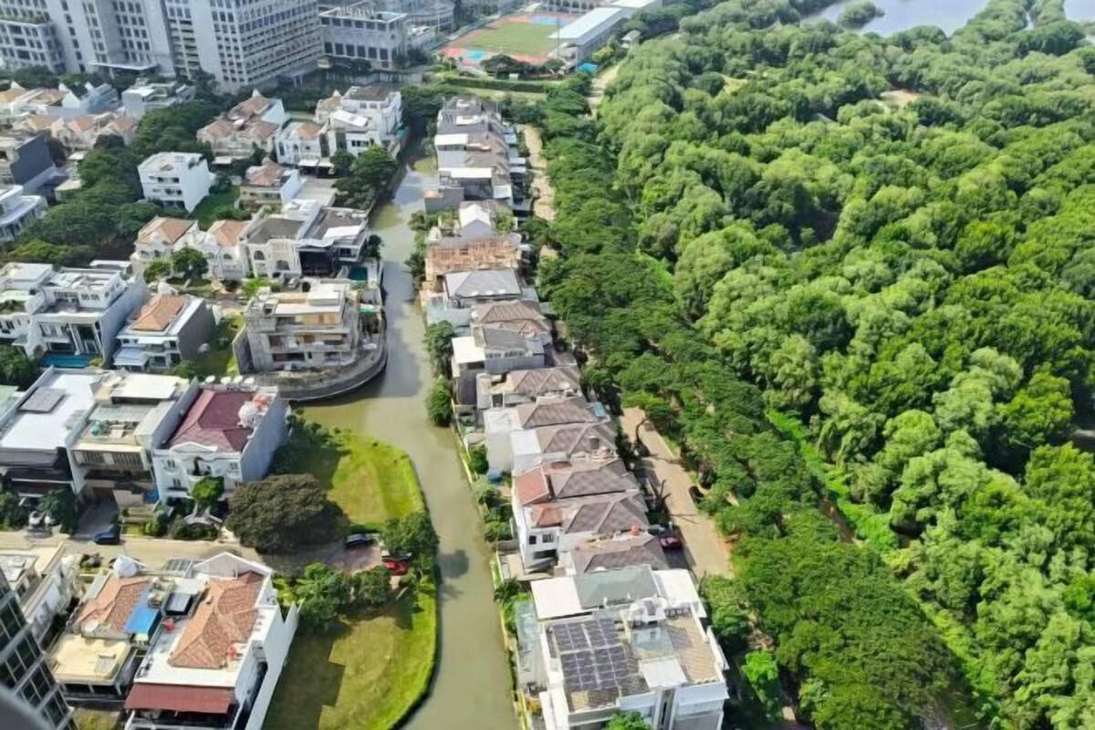 Un quartier résidentiel bordé de maisons le long d’un cours d’eau étroit, entouré d’une végétation luxuriante.
