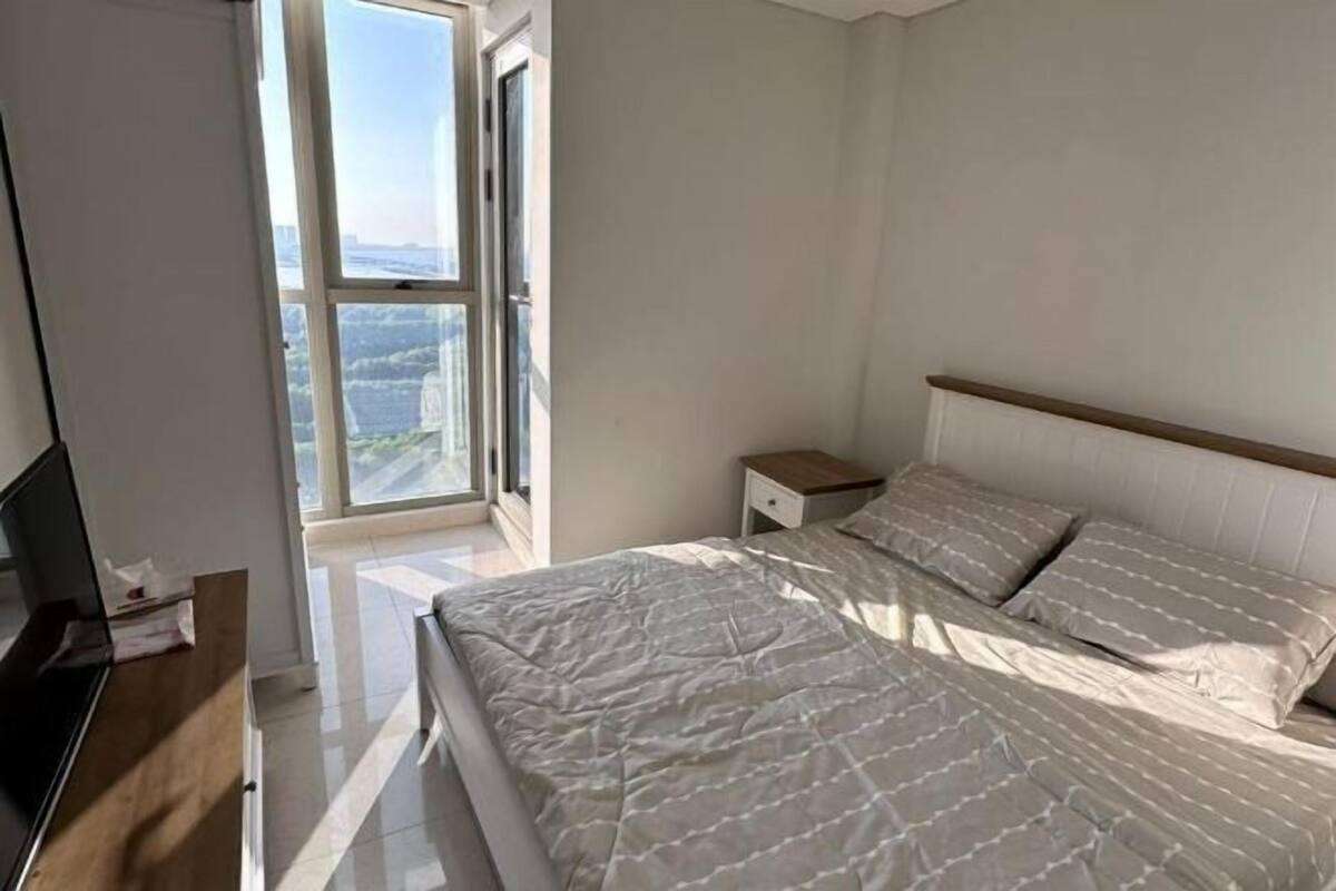 Une chambre avec un grand lit, une table de chevet, une télévision et une fenêtre donnant sur la ville.