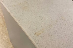 Gros plan d’une surface à la texture particulière et de couleur claire, qui pourrait être un comptoir ou une table.