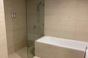 Une salle de bain moderne avec une douche à parois de verre, une baignoire blanche et des carreaux de couleur beige.