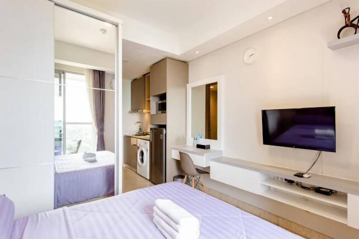 Une chambre d’hôtel moderne équipée d’un lit, d’une télévision, d’un bureau et d’une kitchenette.