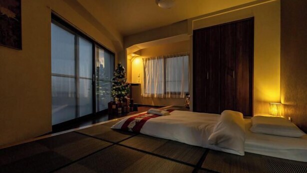 A hotel room with tatami flooring, a bed, a Christmas tree, and a large window. - OHAYO Hotel・Kami-Itabash (Tokyo)
