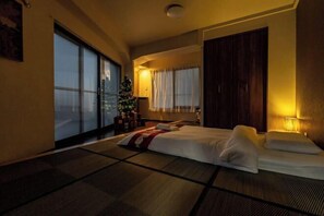 A hotel room with tatami flooring, a bed, a Christmas tree, and a large window.