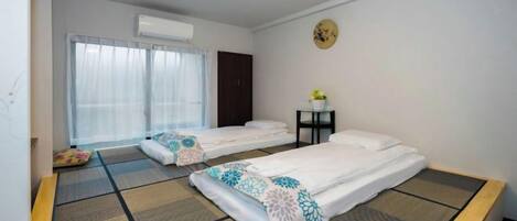 Habitación de hotel con dos camas, una mesita pequeña y una ventana con cortinas.