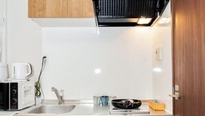 A modern kitchen with a microwave, coffee maker, and a sink. - OHAYO Hotel・Kami-Itabash (Tokyo)