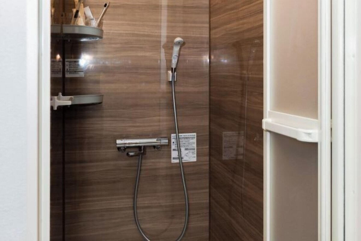 A shower area with a handheld showerhead and a wall-mounted faucet.