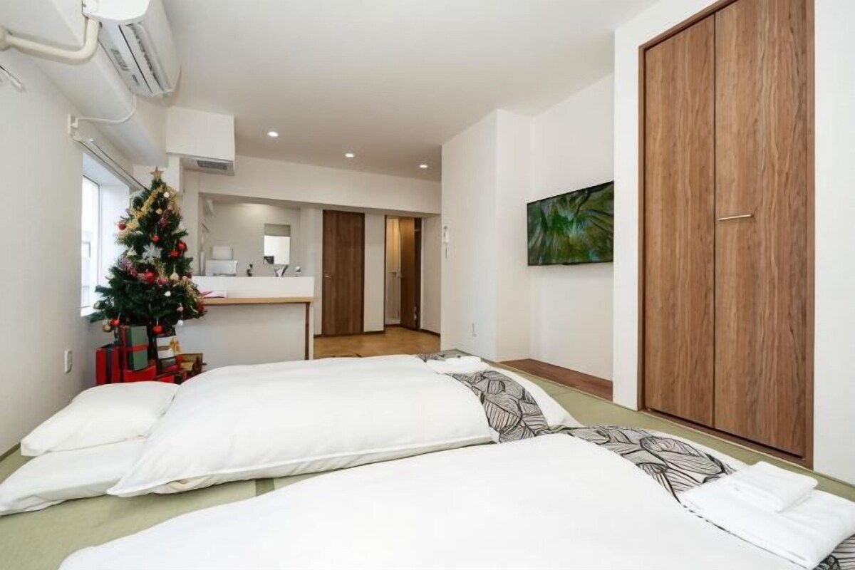 Une chambre avec deux lits, un sapin de Noël et une armoire en bois.