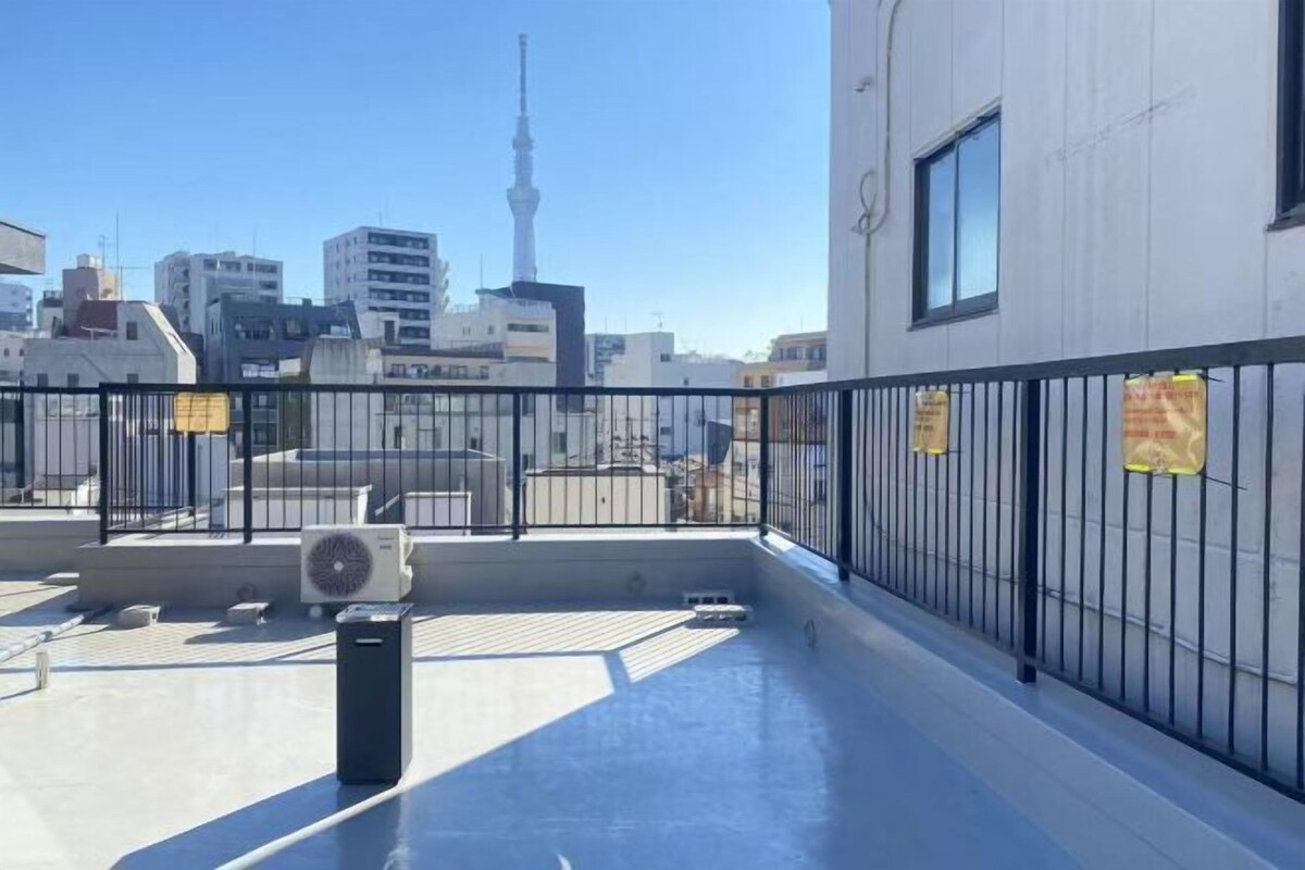 A rooftop terrace with a view of a city skyline, including a prominent tower.