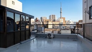 A rooftop terrace with a clear view of a city skyline, including a prominent tower. - OHAYO・AN (Tokyo)