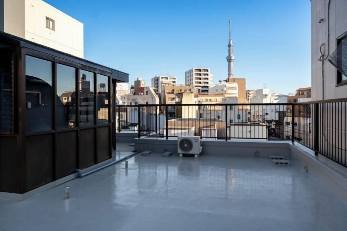 A rooftop terrace with a clear view of a city skyline, including a prominent tower.