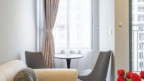 A modern living room with a sofa, two armchairs, a small round table, and a window with curtains. - SOHO Tower Apartment Hotel (Ho Chi Minh City)