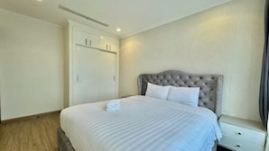A bedroom with a large bed, a wardrobe, and a nightstand. - SOHO Tower Apartment Hotel (Ho Chi Minh City)