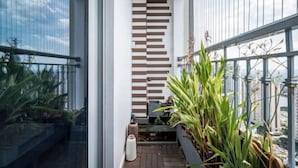 A modern balcony with a view of the city, a wooden slat wall, and potted plants. - SOHO Tower Apartment Hotel (Ho Chi Minh City)