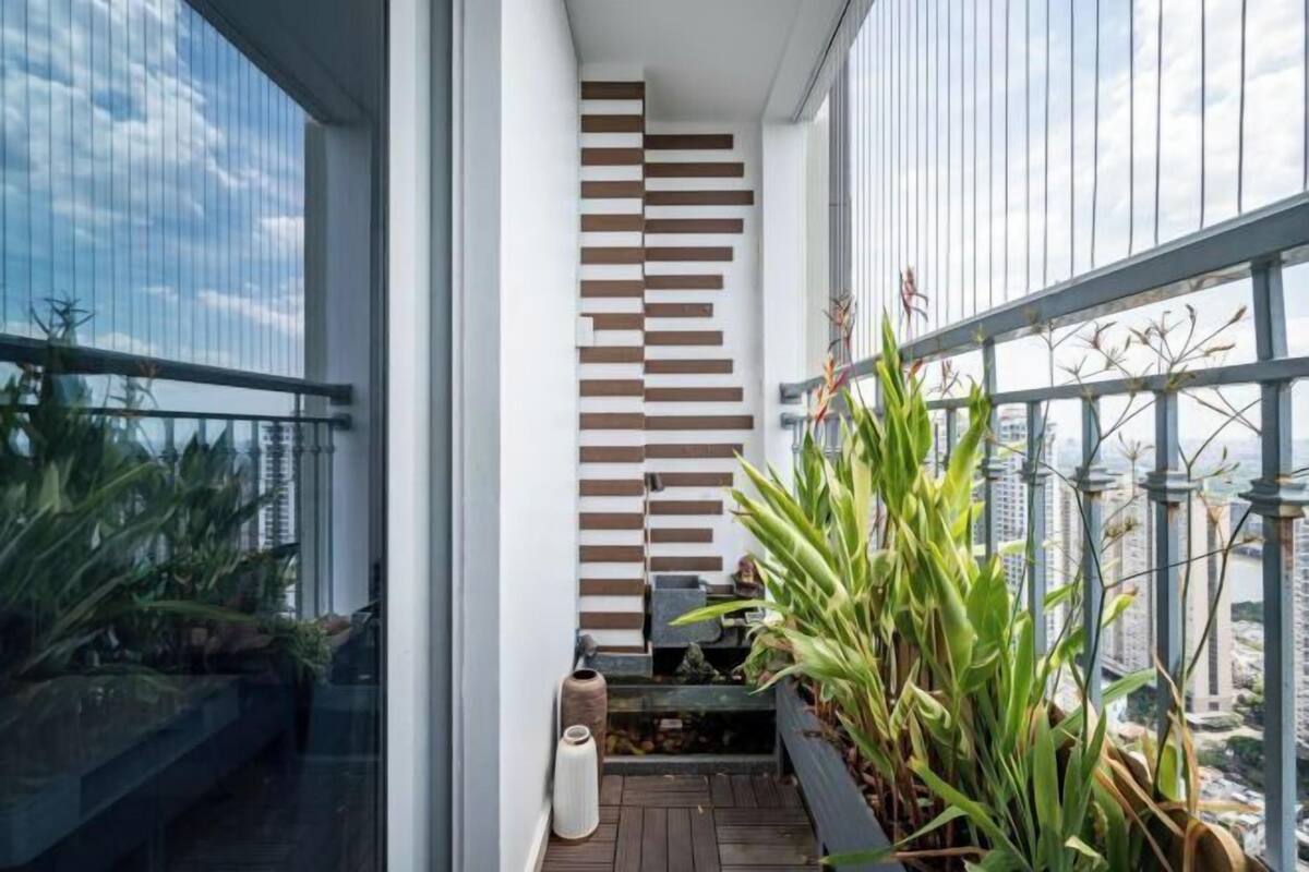 Un balcon moderne offrant une vue sur la ville, avec un mur en lambris de bois et des plantes en pot.