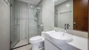 A modern bathroom with a glass shower enclosure, a toilet, and a white sink. - SOHO Tower Apartment Hotel (Ho Chi Minh City)
