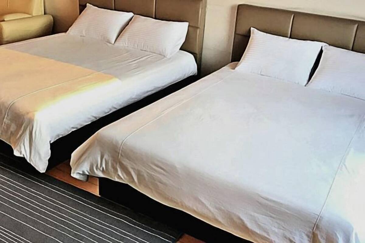 Two beds with white linens, a headboard, and a striped carpet.