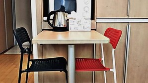 Et lille tekøkken med kaffemaskine, teposer og to stole.