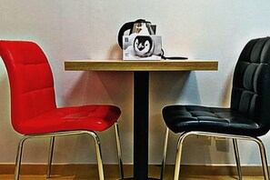 Twee stoelen, één rood en één zwart, met een tafel ertussen.
