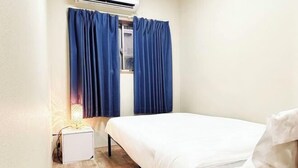 Un dormitorio con cama, mesita de noche, lámpara y ventana con cortinas.