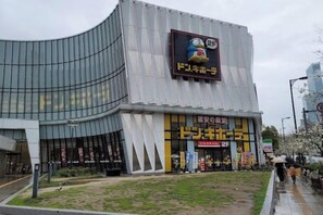 Ein modernes Gebäude mit einer gewölbten Fassade, großer Beschilderung und einer kleinen Außenbestuhlung.